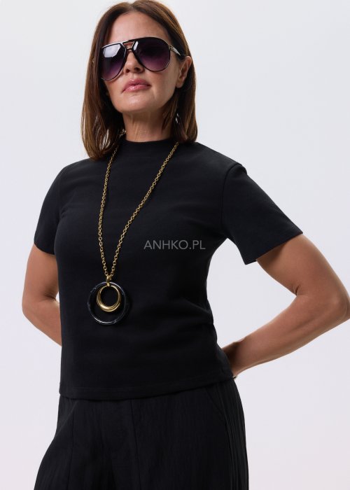 Czarna bluzka damska z krótkim rękawem o prostym kroju, minimalistyczny fason, stylizacja z czarnymi spodniami i biżuterią.