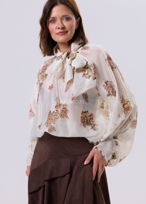 Jasnobeżowa bluzka Liora Bloom z kwiatowym nadrukiem, dekolt V-neck, luźny fason za biodra i koronkowe wykończenie w stylu boho.