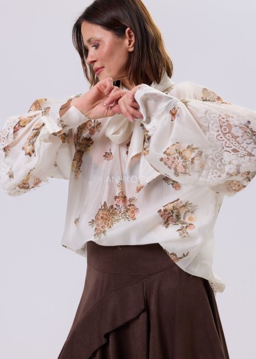 Jasnobeżowa bluzka Liora Bloom z kwiatowym nadrukiem, dekolt V-neck, luźny fason za biodra i koronkowe wykończenie w stylu boho.