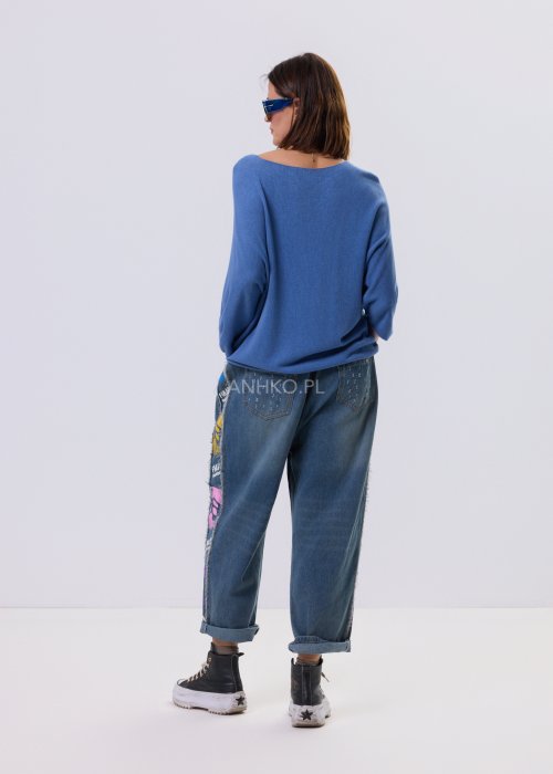 Niebieski sweter damski o nietoperzowym kroju z dekoltem V i rękawem 3/4, zestawiony z luźnymi jeansami i trampkami w casualowej stylizacji.