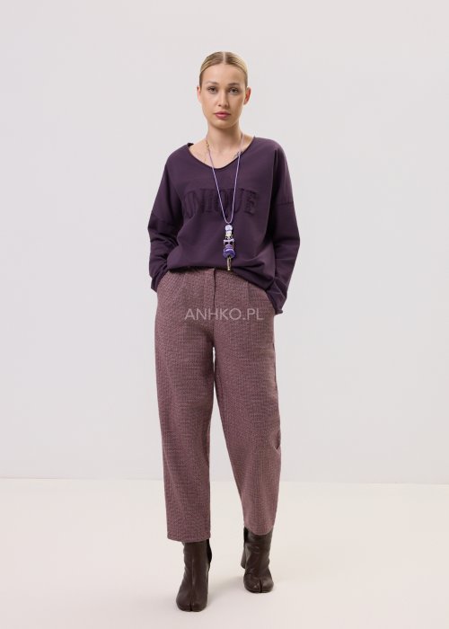 Śliwkowa bluzka Script Longsleeve z długim rękawem i luźnym fasonem, z napisem na przodzie, zestawiona z eleganckimi spodniami w kobiecej stylizacji.