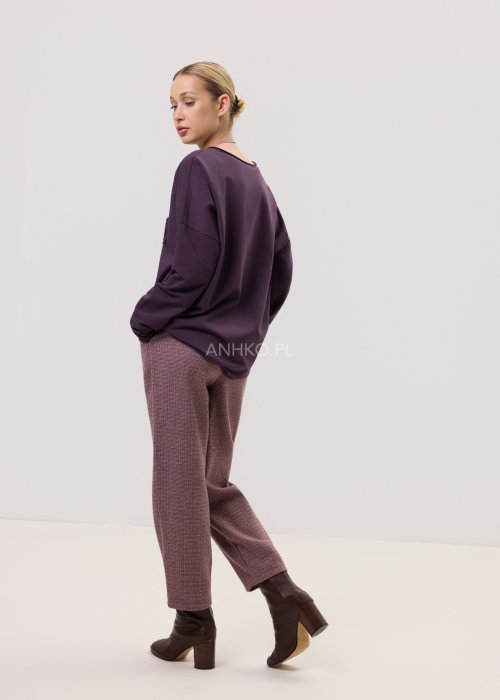 Śliwkowa bluzka Script Longsleeve z długim rękawem i luźnym fasonem, z napisem na przodzie, zestawiona z eleganckimi spodniami w kobiecej stylizacji.