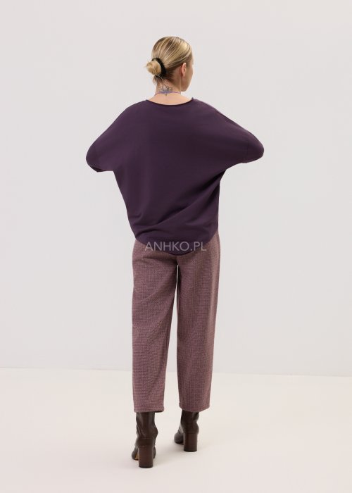 Śliwkowa bluzka Script Longsleeve z długim rękawem i luźnym fasonem, z napisem na przodzie, zestawiona z eleganckimi spodniami w kobiecej stylizacji.