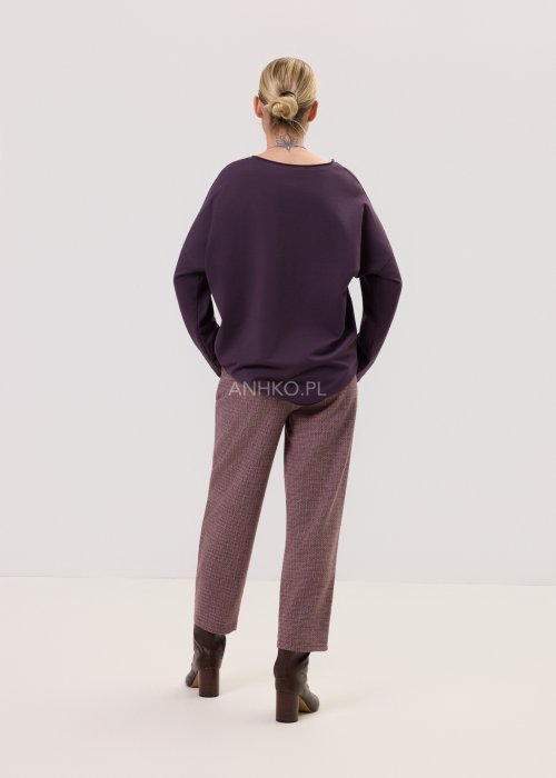 Śliwkowa bluzka Script Longsleeve z długim rękawem i luźnym fasonem, z napisem na przodzie, zestawiona z eleganckimi spodniami w kobiecej stylizacji.