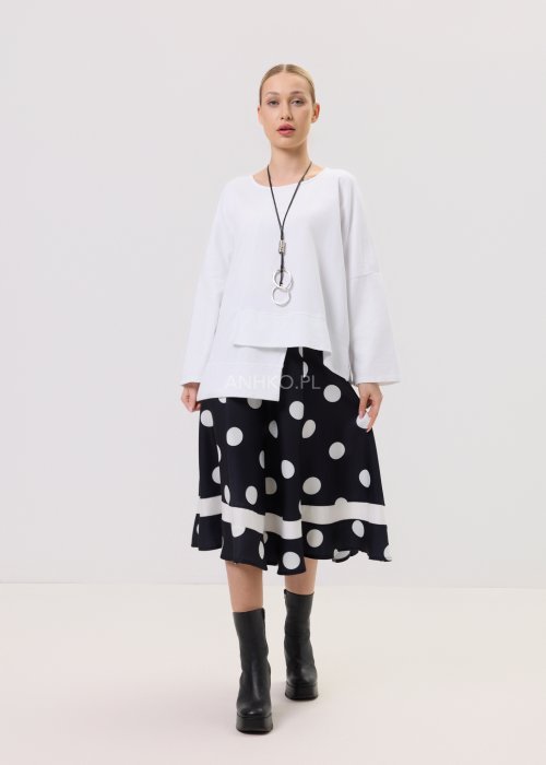 Biała bluza oversize damska z asymetrycznym dołem i szerokim rękawem. Stylizacja z czarną spódnicą w grochy w nowoczesnym, minimalistycznym stylu.