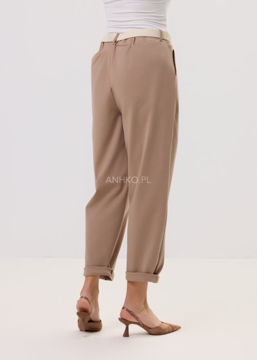 Spodnie Starola Rose Cappuccino w odcieniu ciepłego beżu, z podwiniętą nogawką i eleganckim paskiem, w minimalistycznej stylizacji z butami na obcasie.