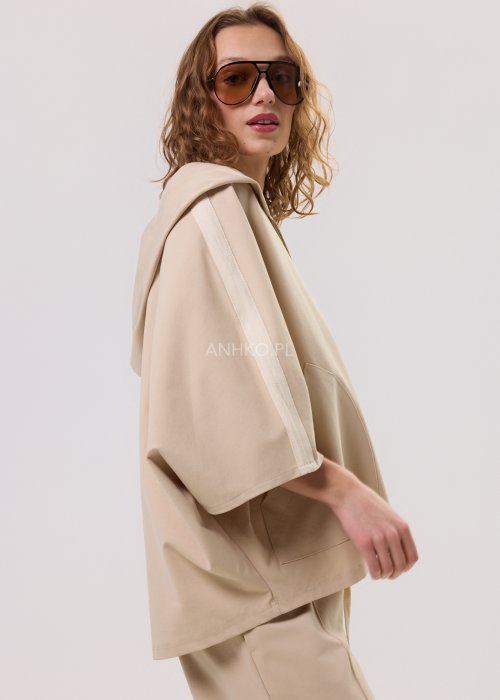 Beżowa bluza damska o luźnym, oversize’owym kroju z kapturem. Model zapinany na zamek, z krótkim rękawem typu kimono oraz naszytymi kieszeniami z przodu, wykonany z miękkiej, komfortowej dzianiny.