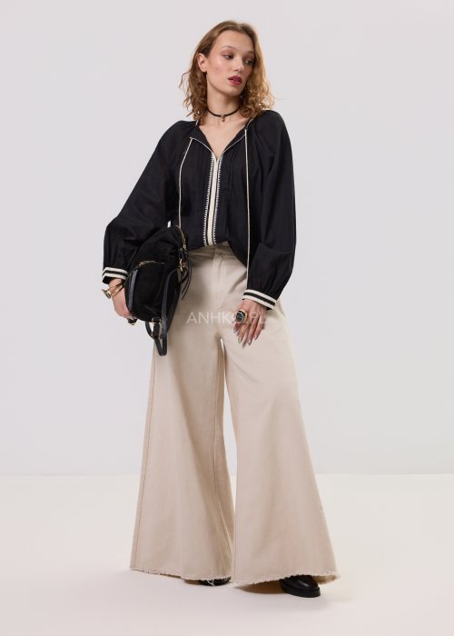 Czarna bluzka damska z ozdobną lamówką, dekoltem V oraz wiązaniem z frędzlami, o luźnym kroju i długim rękawie.