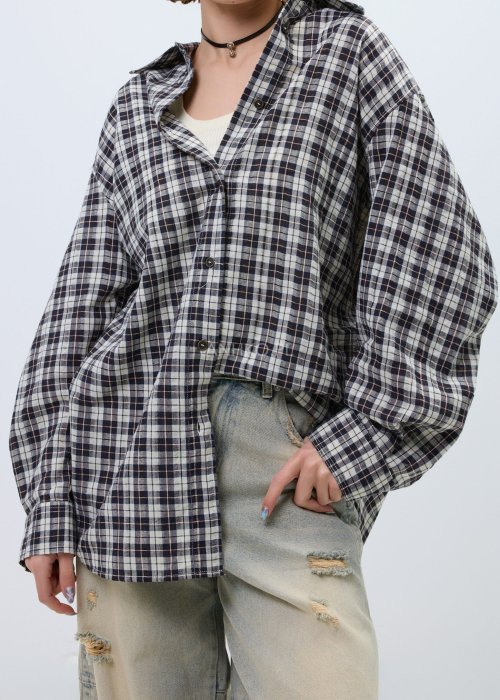 Koszula damska oversize w kratę, zapinana na guziki, stylizowana z jasnymi jeansami z przetarciami.