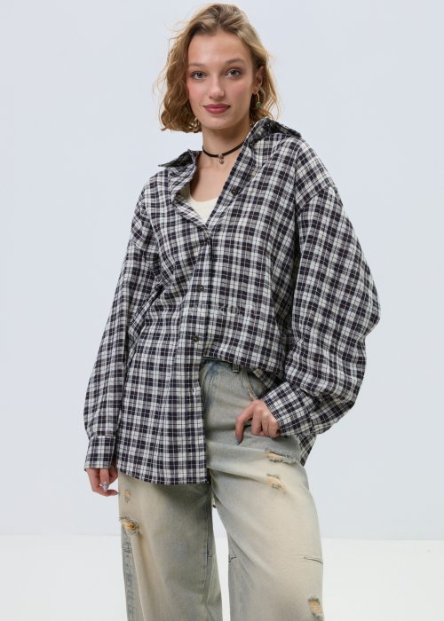 Koszula damska oversize w kratę, zapinana na guziki, stylizowana z jasnymi jeansami z przetarciami.