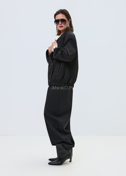 Czarne damskie spodnie garniturowe z szeroką nogawką, elegancki model z wysokim stanem i zakładkami z przodu w minimalistycznej stylizacji.