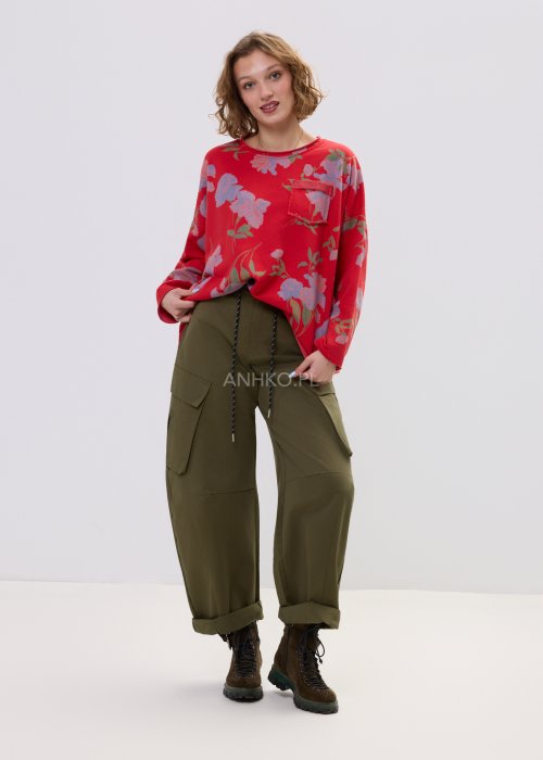 Czerwona bluza damska w kwiaty o luźnym kroju z długim rękawem i kieszonką na piersi, zestawiona z oliwkowymi spodniami w stylu casual.