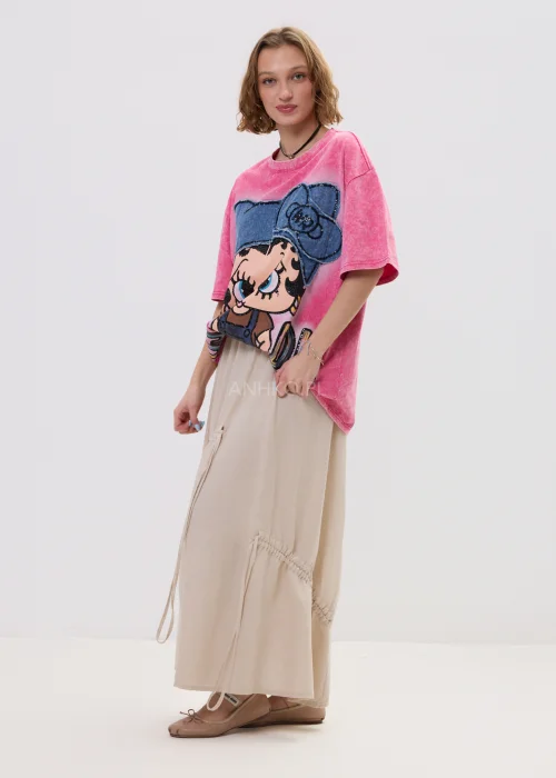 Różowy t-shirt damski oversize z nadrukiem postaci i cekinowymi detalami, luźny fason – stylizacja ze spódnicą.