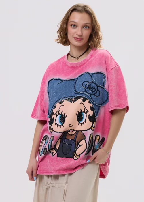 Różowy t-shirt damski oversize z nadrukiem postaci i cekinowymi detalami, luźny fason – stylizacja ze spódnicą.
