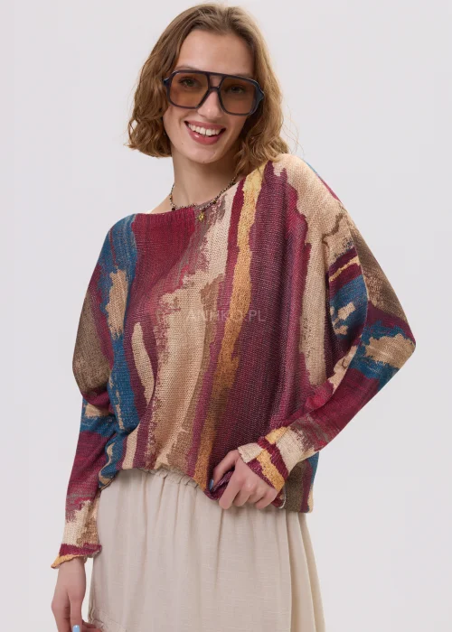 Sweter oversize w wielokolorowy, artystyczny print – odcienie bordo, beżu i niebieskiego, luźny fason, stylizacja z jasną spódnicą.