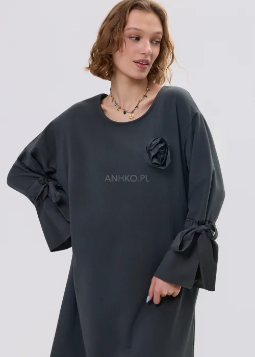 Ciemnoszara sukienka oversize midi z szerokimi rękawami i wiązaniami, ozdobny kwiat na piersi, stylizacja z botkami.