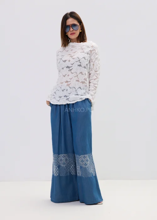 Biała bluzka damska z koronkową strukturą i długim rękawem, lekko transparentny materiał, styl casual.