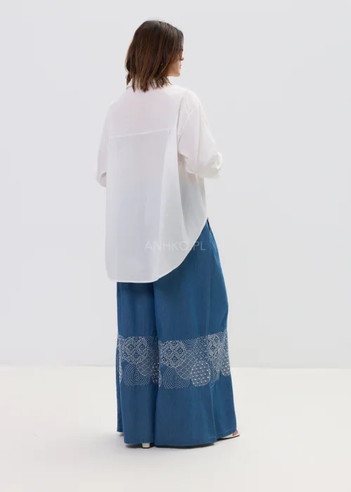 Biała koszula damska z haftowaną aplikacją róży, luźny fason, lekko transparentny materiał, elegancki styl.