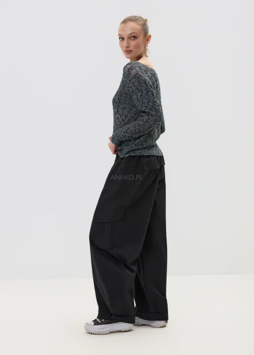Melanżowy sweter o luźnym kroju z ażurową strukturą, w odcieniach szarości stylizowany z czarnymi spodniami w minimalistycznym looku.