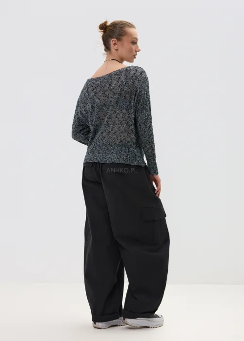 Melanżowy sweter o luźnym kroju z ażurową strukturą, w odcieniach szarości stylizowany z czarnymi spodniami w minimalistycznym looku.