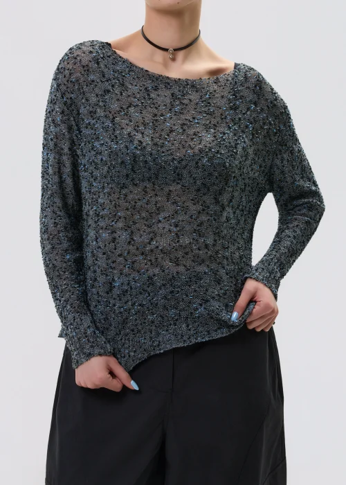 Melanżowy sweter o luźnym kroju z ażurową strukturą, w odcieniach szarości stylizowany z czarnymi spodniami w minimalistycznym looku.