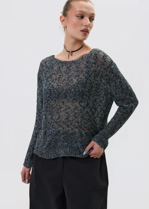 Melanżowy sweter o luźnym kroju z ażurową strukturą, w odcieniach szarości stylizowany z czarnymi spodniami w minimalistycznym looku.