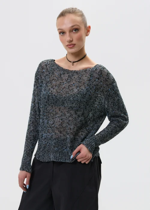 Melanżowy sweter o luźnym kroju z ażurową strukturą, w odcieniach szarości stylizowany z czarnymi spodniami w minimalistycznym looku.