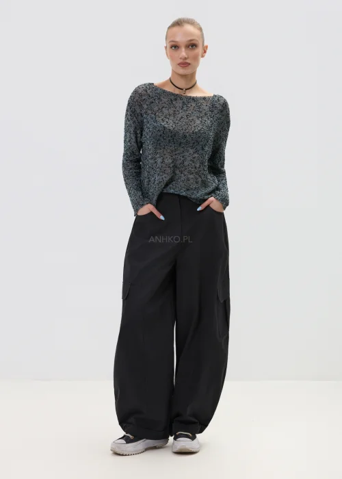 Melanżowy sweter o luźnym kroju z ażurową strukturą, w odcieniach szarości stylizowany z czarnymi spodniami w minimalistycznym looku.
