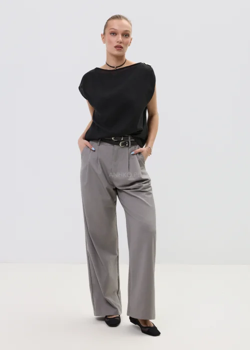 Czarna bluzka damska bez rękawów z luźnym krojem i ozdobnym zapięciem na ramieniu, elegancka minimalistyczna stylizacja.