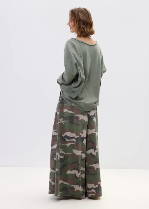 Szerokie spodnie damskie w militarny wzór moro z wysokim stanem i zakładkami w pasie, w stylizacji z paskiem i sneakersami.