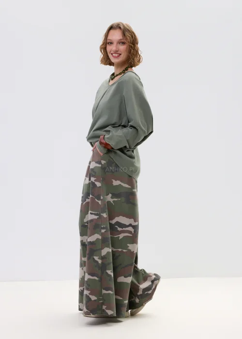Szerokie spodnie damskie w militarny wzór moro z wysokim stanem i zakładkami w pasie, w stylizacji z paskiem i sneakersami.