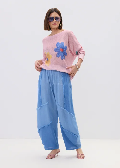 Pudrowo różowy sweter o lekkim, luźnym splocie z kolorowym motywem kwiatów, zestawiony z niebieską spódnicą w casualowej stylizacji.