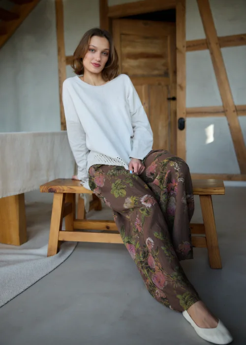Szerokie spodnie damskie z wysokim stanem w brązowym kolorze z kwiatowym wzorem, o luźnym, lejącym kroju z elastyczną talią, stylizacja w naturalnym, boho klimacie.