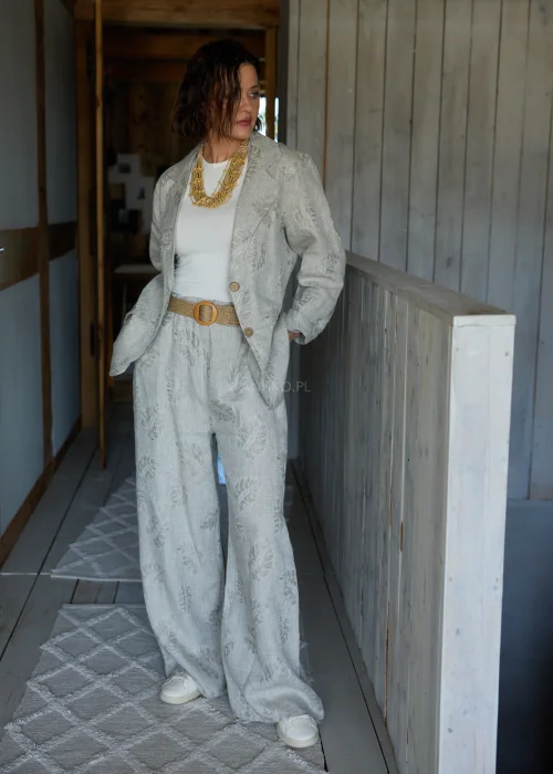 Lniana marynarka w szarym kolorze z subtelnym roślinnym wzorem, o luźnym kroju, stylizowana w komplecie ze spodniami w tym samym materiale w eleganckim, naturalnym wydaniu.
