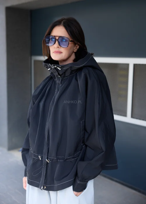 Czarna kurtka oversize z kapturem i kontrastowymi przeszyciami. Lekki model o sportowo-miejskim charakterze z regulacją w talii, idealny do nowoczesnych stylizacji casualowych i streetwearowych.