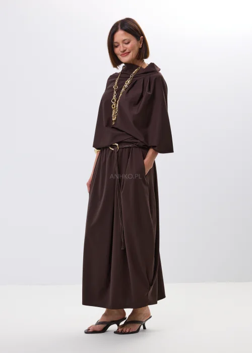 Brązowa bluzka o nowoczesnym, asymetrycznym fasonie z efektownym układaniem przy dekolcie. Miękko opływa sylwetkę i nadaje stylizacji eleganckiego charakteru.