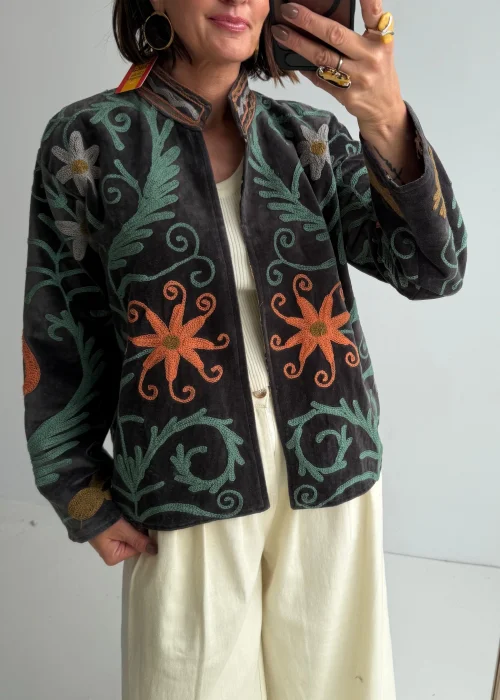 Żakiet boho w grafitowym kolorze ozdobiony kolorowymi haftami kwiatowymi i roślinnymi motywami. Krótki model z długim rękawem i stójką doskonale uzupełnia artystyczne oraz casualowe stylizacje.