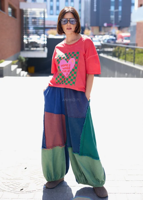 Damski t-shirt oversize w kolorze malinowym z kolorowym nadrukiem i napisem „Home is where the art is” w casualowej stylizacji.