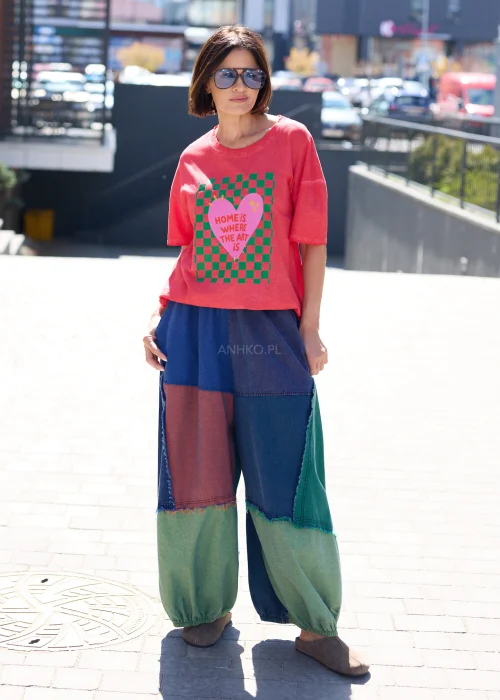 Damski t-shirt oversize w kolorze malinowym z kolorowym nadrukiem i napisem „Home is where the art is” w casualowej stylizacji.