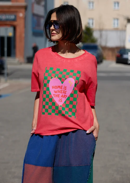 Damski t-shirt oversize w kolorze malinowym z kolorowym nadrukiem i napisem „Home is where the art is” w casualowej stylizacji.