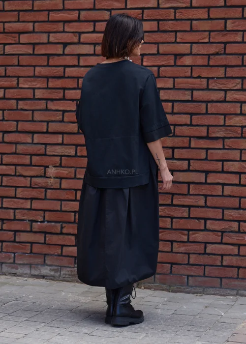 Czarna sukienka oversize midi z szerokim rękawem i minimalistycznym fasonem w nowoczesnej miejskiej stylizacji.