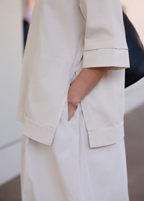 Beżowa sukienka oversize midi z krótkim rękawem i minimalistycznym fasonem w nowoczesnej miejskiej stylizacji.