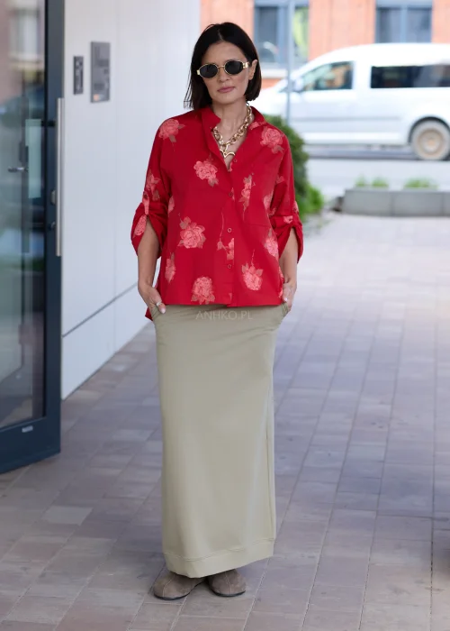 Damska czerwona koszula oversize z różanym printem, kieszenią na piersi i podwijanymi rękawami. Elegancka stylizacja z oliwkową spódnicą podkreśla kobiecy, nowoczesny charakter outfitu.