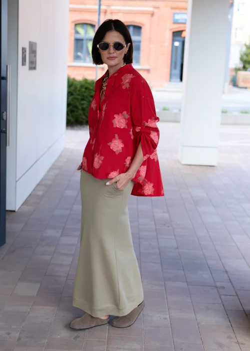 Damska czerwona koszula oversize z różanym printem, kieszenią na piersi i podwijanymi rękawami. Elegancka stylizacja z oliwkową spódnicą podkreśla kobiecy, nowoczesny charakter outfitu.