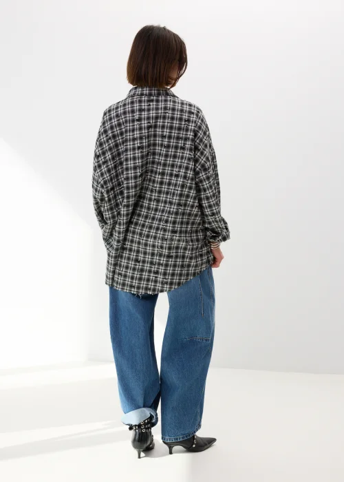 Oversize’owa koszula damska w czarno-białą kratę z efektem delikatnych przetarć i surowym wykończeniem. Luźny fason w stylu grunge świetnie komponuje się z jeansami wide leg i miejskimi stylizacjami casual.