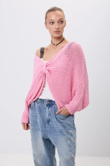 Różowy sweter damski o ażurowym splocie z luźnym fasonem i szerokimi rękawami. Model można nosić klasycznie lub jako narzutkę z efektownym wiązaniem z przodu.