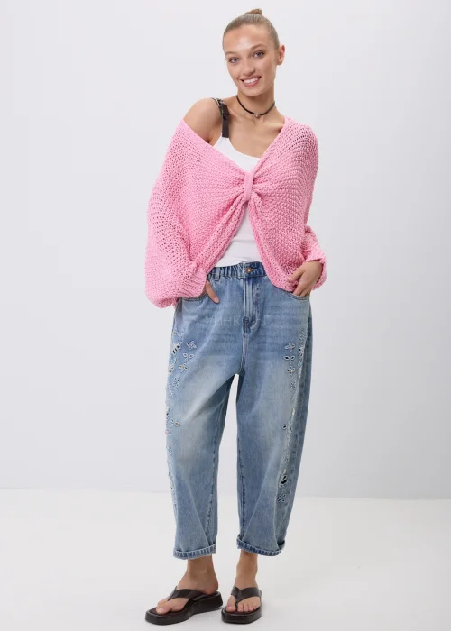 Różowy sweter damski o ażurowym splocie z luźnym fasonem i szerokimi rękawami. Model można nosić klasycznie lub jako narzutkę z efektownym wiązaniem z przodu.