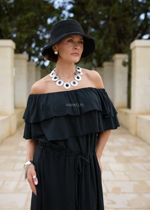 Czarna sukienka maxi hiszpanka z efektownymi falbanami przy dekolcie i regulacją w talii. Elegancka stylizacja z odkrytymi ramionami, kapeluszem i wyrazistą biżuterią w minimalistycznym wydaniu.