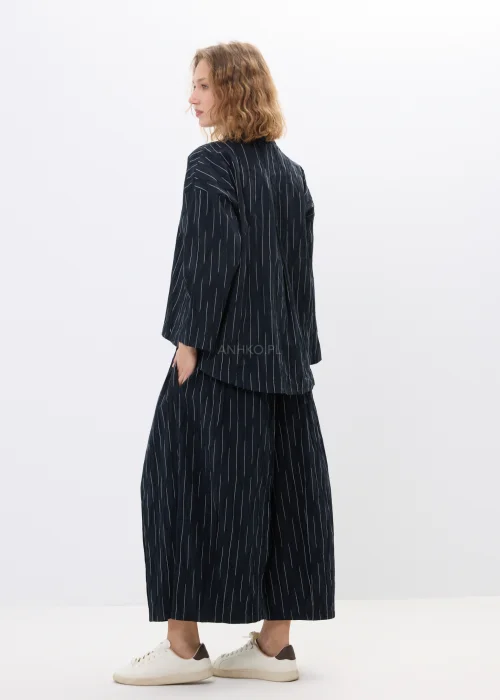 Czarno-biała marynarka oversize w delikatne paski z lekkiego materiału o nowoczesnym fasonie. Luźny model z długim rękawem idealny do eleganckich i casualowych stylizacji.