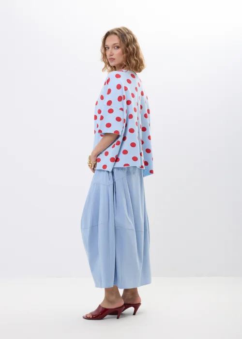 Niebieska bluzka oversize w czerwone grochy z krótkim rękawem i luźnym fasonem. Lekki materiał pięknie układa się na sylwetce, tworząc kobiecą stylizację w retro klimacie z wyrazistym printem.